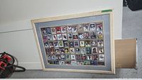 Overall view of the framed collection showing the wooden frame, matting, and grid of cards behind glass.