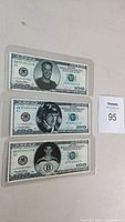 Three $100 bills showing portraits of hockey players Gordie Howe, Bobby Orr, and Wayne Gretzky in hockey uniform.