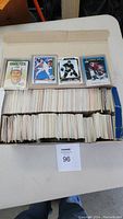 Open shoebox showing hundreds of sports cards with four cards displayed on top, featuring hockey and baseball players.