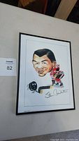 Front view of framed caricature artwork signed by Stan Mikita, showing the caricature in Chicago Blackhawks uniform with hockey stick and puck.