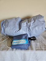 Light blue folded inflatable air mattress with attached electric pump and control switch, includes blue carry/storage bag with Aerobed label.
