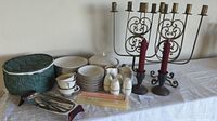 Photo showing the full set including brass candelabras, P.B. Rogers silver candlesticks, Flintridge china with bowls, teacups, sugar and creamer, taurine with lid, salt and pepper shakers, and silverware on a table with a green padded storage bag