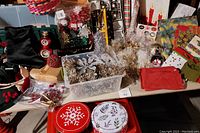 Wide view of assorted vintage Christmas holiday decorations including garlands, candles, wrapping paper, and containers, showing general contents of the lot.