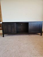 Front view of the dark wood Room and Board entertainment cabinet showing two closed doors and open center compartments