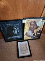 Three framed art pieces: Spiritualized concert poster, Star Wars Chewbacca and Han Solo poster, and Lobster Babe original art.