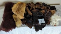 Overview of assorted fur pelts laid out including brown mink, reddish-brown fox, dark and light pelts, white rabbit fur visible on right