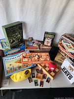 Photo of the collection of boxed games and game components arranged on a table, including various board, card games, and game pieces.