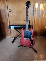 Red electric guitar and Proline adjustable bench together showing overall size and condition