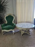 Photo of the round marble top table and green velvet upholstered chair beside it