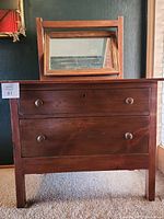 Front view of wooden mini dresser with two drawers and mirror on top