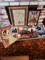 View of entire lot of music posters showing two framed posters and five loose posters arranged on a patterned fabric covering.