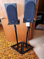 Front view of pair of Pioneer speakers on metal stands with black fabric grills and black wood finish.