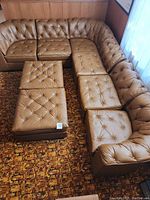 Top-down view of large 8-piece brown pleather sectional couch arranged in corner shape showing tufted cushions and corner seats with backs.