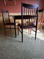 Angled view of round table with three spindle-back chairs on floor