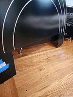 Close-up of the lower portion of the black headboard showing silver striping and wooden floor beneath.