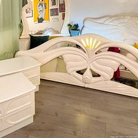 View of the lighted headboard with an illuminated sunburst panel showing some burn damage and intricate carving details.