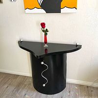 Full front view of the black half-circle table with silver wooden spheres and squiggle.