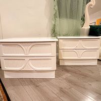 Pair of white 1980s postmodern Italian nightstands showing front and side views on floor near a green curtain and patterned rug.