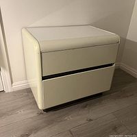 Front perspective of white lacquer vintage nightstand showing two drawers and curved waterfall design