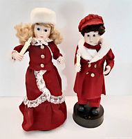 Front view of both Victorian style Christmas caroler figures, showing clothing and candle props