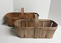Two vintage wooden produce baskets shown side by side on a white background, showing overall shape and handles.