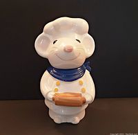 Front view of the white ceramic Pierre Mouse cookie jar dressed as a chef holding a rolling pin with smiling face and blue neckerchief.