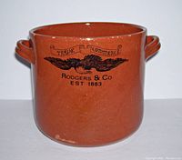 Front view of redware crock showing brown ceramic body, two handles, and black eagle logo with text.