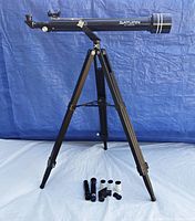 Saturn telescope mounted on adjustable tripod with lenses and accessories displayed in front.