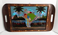 Full view of wooden tray with cut-out handles, showing South America map and scenic background under glass.