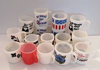 Front view of assortment of 18 vintage coffee mugs in varying designs and colors, including red and milk glass styles