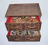 Front view of box with top drawers open showing mixed jewelry contents in top compartments