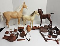 Three horses and various plastic accessories arranged on white background