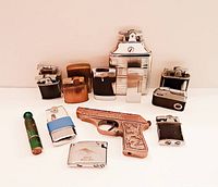 Group photo of 14 assorted vintage lighters showing various styles and finishes including the gun-shaped copper lighter and green cylindrical lighter
