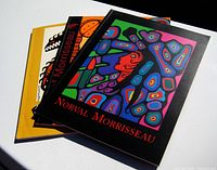 Three stacked art gallery books featuring Norval Morrisseau artwork on the covers, showing colorful Indigenous designs.