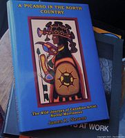 Blue hardcover book with dust jacket featuring indigenous artwork on front cover and title in yellow font.