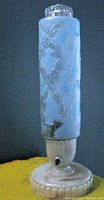 Full view of blue frosted art glass tower lamp on Bakelite base against wall.