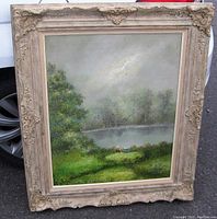 Overall oil painting view in ornate gilt wood frame with lake scene and two figures near water.