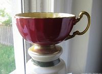 Side view showing the burgundy maroon exterior and ornate gold handle of the Aynsley tea cup.