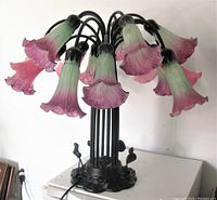 Front view of unlit lamp showing 12 flared lily-shaped glass shades on metal base