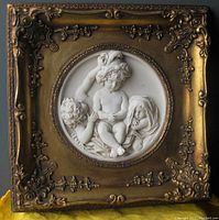 Full frontal view of the Old Italian alabaster bas relief wall hanging, showing the ornate gold-toned frame and three children figures inside a circular relief.