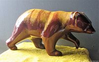 Side profile of ceramic bear statue showing glossy brown and yellow glaze.