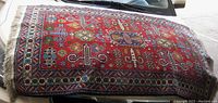 Full view of rug draped over vehicle hood showing overall pattern and fringe