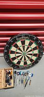 Front view of Eastpoint Derbyshire dart board with darts and wooden box nearby.