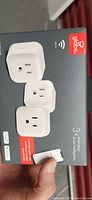 Front view of box showing three white smart plugs and Globe brand logo, indicates 3 smart plugs inside.