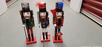 Full view of the three large wooden nutcrackers standing on a floor, showing all figurines from front.