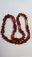 Full view of amber bead necklace laid out on white background.