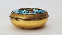 Side angle showing the gilt metal base and the raised cloisonné dragon lid with blue enamel waves, confirming good condition and size.