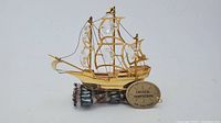 Gold plated sailing boat miniature figurine decorated with clear Austrian crystals and a tag named 'Crystal Temptations 24K Gold Plated'. The figurine is shown resting on a decorative stone base, which is not included in the lot.
