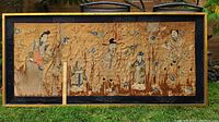 Full front view of framed large rectangular tapestry depicting six figures of temple gods embroidered on worn golden silk fabric with surrounding floral embroidery.