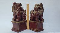 Front view of pair of red glazed porcelain foo dogs with ruler showing about 15 inches height.